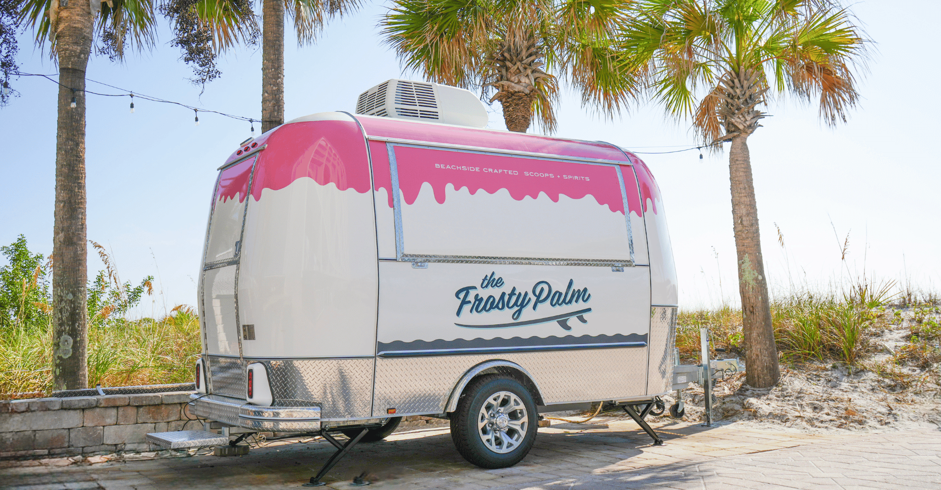 A white and pink Airstream-style food trailer branded 