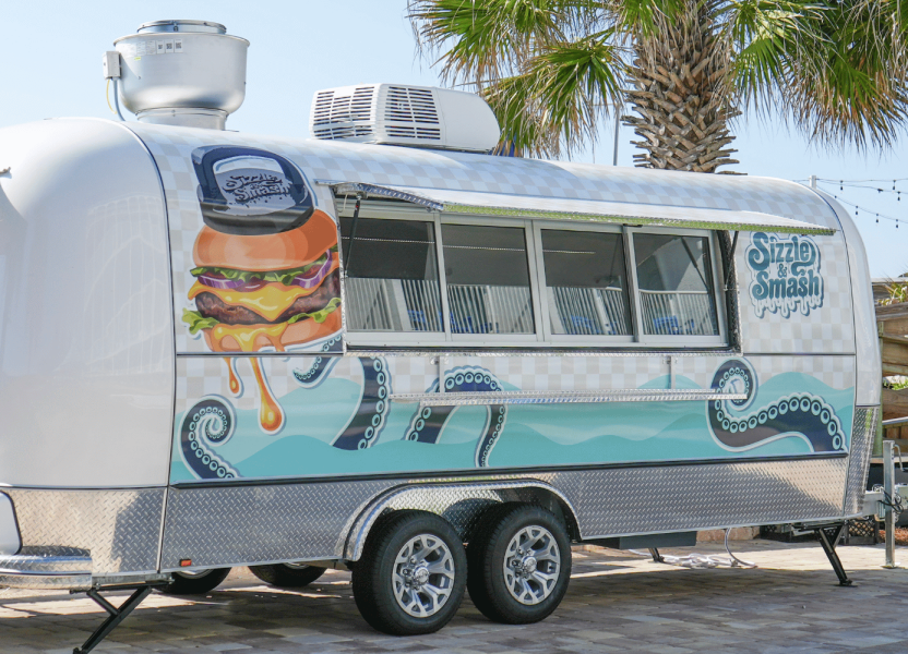 A silver Airstream-style food truck branded 